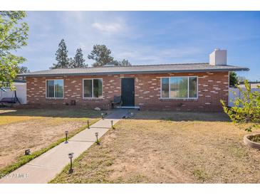 Charming single-story brick home featuring a well-manicured lawn and inviting walkway at 3107 W Tuckey Ln, Phoenix, AZ 85017