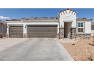 Charming single-story home with a three-car garage, stone accents, and a well-maintained front yard at 5134 W Western Star Blvd, Laveen, AZ 85339