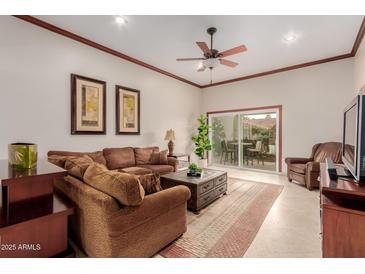 Inviting living room featuring a comfortable brown sofa, ceiling fan, and sliding doors to the outdoor patio at 8749 E Via De Sereno --, Scottsdale, AZ 85258