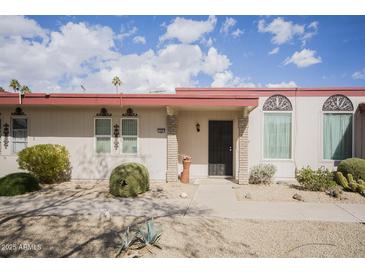 Charming home exterior featuring desert landscaping, a red trim, and shaded front entry at 12887 N 99Th Dr, Sun City, AZ 85351