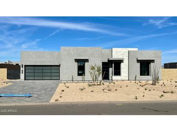 Contemporary home with a desert landscape, gray stucco and a glass garage door at 13278 E Buckskin Trl, Scottsdale, AZ 85255