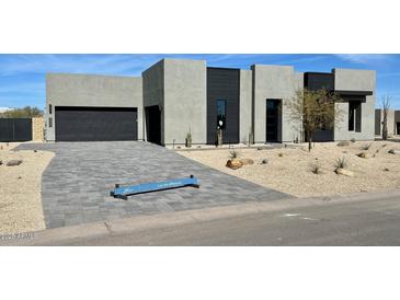 Contemporary home featuring a desert landscape, neutral color palette, and a driveway made of gray pavers at 13302 E Buckskin Trl, Scottsdale, AZ 85255