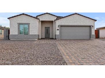 Charming stucco home with a two-car garage and patterned brick driveway at 14240 S Overfield Rd, Arizona City, AZ 85123