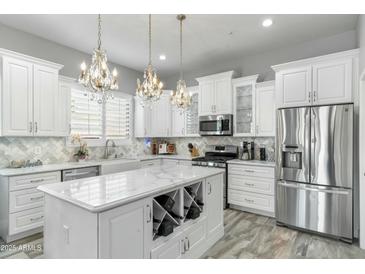 Bright kitchen with white cabinets, marble countertops, stainless steel appliances, and chandeliers at 14442 N Prickly Pear Ct, Fountain Hills, AZ 85268