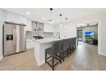 Modern kitchen features white cabinets, stainless steel appliances, patterned backsplash, and a breakfast bar with seating at 1709 W Clarendon Ave, Phoenix, AZ 85015