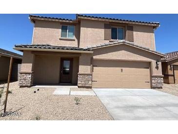 Two-story home showcasing a neutral stucco facade, stone accents, a two-car garage, and a low-maintenance gravel yard at 24569 W St Catherine Ave, Buckeye, AZ 85326