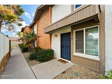 Charming townhome featuring a blue security door and well-maintained landscaping with gravel and a tidy walkway at 5106 N 17Th Ave # 11, Phoenix, AZ 85015