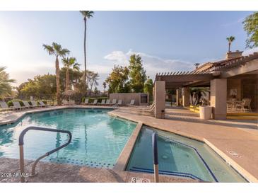 Inviting community pool with lounge chairs, palm trees, and a spa for relaxation and recreation at 9445 N 94Th Pl # 201, Scottsdale, AZ 85258