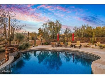 Inviting pool area with desert landscaping, lounge seating and beautiful sunset views at 9962 E Groundcherry Ln, Scottsdale, AZ 85262