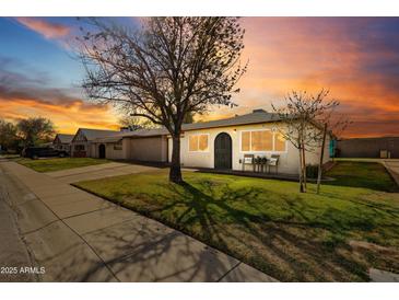 Cozy single-story home with neat front yard and sidewalk, highlighted by a dramatic sky at sunset at 10324 N 97Th Dr # B, Peoria, AZ 85345