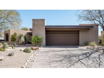 Desert home with a two-car garage and xeriscaped front yard with native plants and rock features at 10687 E Fernwood Ln, Scottsdale, AZ 85262