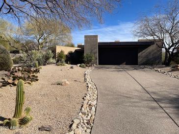 Contemporary home featuring desert landscaping, a spacious driveway, and an attached two car garage at 10687 E Fernwood Ln, Scottsdale, AZ 85262