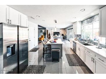 Modern kitchen featuring stainless steel appliances, ample white cabinetry, and a spacious island with barstool seating at 11215 N 37Th Ave, Phoenix, AZ 85029