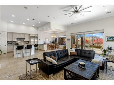 Bright and airy living room featuring a large sectional sofa, tile flooring, and seamless flow to the kitchen and dining areas at 10883 E La Junta Rd, Scottsdale, AZ 85255