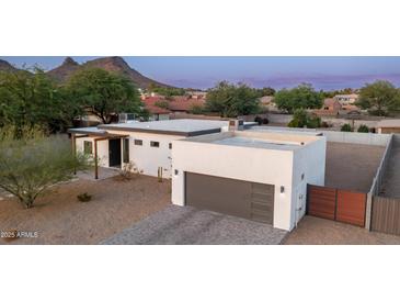 Beautiful modern home with a gray garage door, desert landscaping, and mountain views at 14025 N 11Th Pl, Phoenix, AZ 85022