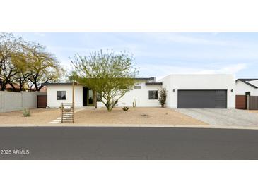 Contemporary home with desert landscaping and a gray two-car garage door at 14025 N 11Th Pl, Phoenix, AZ 85022