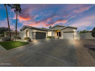 Stunning single-story home with a three-car garage and beautiful desert landscaping, showcasing a picturesque desert sunset at 14474 W Lexington Ave, Goodyear, AZ 85395