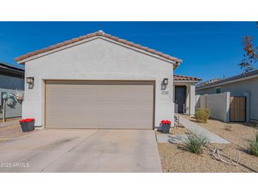Charming single-story home featuring a neutral color scheme, two car garage, and a well-manicured front yard at 17342 W Patrick Ln, Surprise, AZ 85387