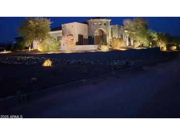 Night shot of well-lit home with desert landscaping including cacti and trees at 31409 N 166Th Pl, Scottsdale, AZ 85262