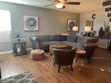 Comfortable living room with a large sectional sofa, stylish chairs, and hardwood floors at 6943 W Devonshire Ave # 1355, Phoenix, AZ 85033
