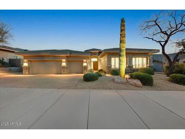 Inviting desert home with stone accents, three-car garage, and lush, low-maintenance landscaping at 10999 E Acoma Dr, Scottsdale, AZ 85255