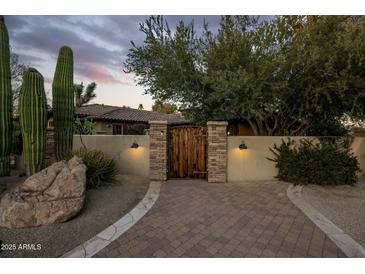Inviting desert home with a lighted courtyard entry featuring a custom wood gate and beautiful desert landscaping at 11021 N 74Th St, Scottsdale, AZ 85260