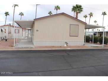 Tan home with awning and landscaping with palm trees in background at 7807 E Main St # F24, Mesa, AZ 85207