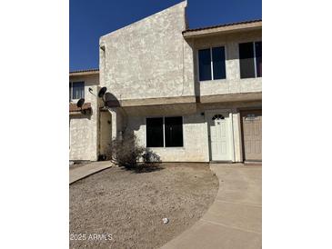 Charming townhome featuring neutral stucco, a front patio, and a classic white front door with address number at 3840 N 43Rd Ave # 76, Phoenix, AZ 85031