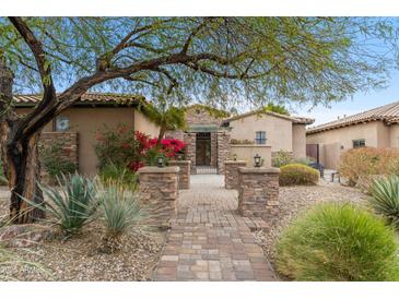 Charming home featuring a stone pathway, lush landscaping, and a secure gated entry at 9869 E Davenport Dr, Scottsdale, AZ 85260