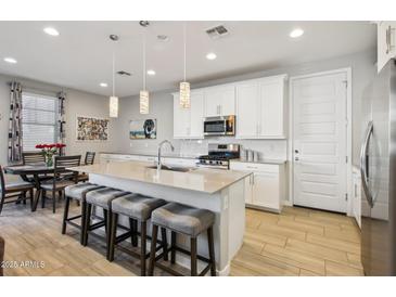 Modern kitchen with white cabinets, stainless steel appliances, a kitchen island, and counter seating at 9923 E Texas Ave, Mesa, AZ 85212