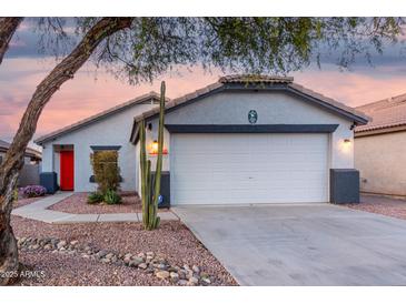 Charming single-story home featuring a two-car garage, desert landscaping, and a bright red front door at 12630 W Aster Dr, El Mirage, AZ 85335