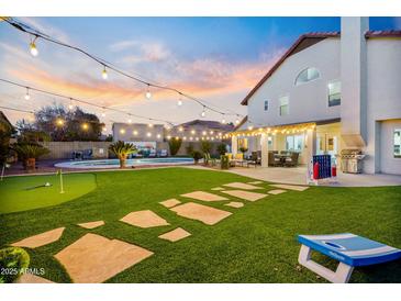 Expansive backyard featuring a pool, putting green, and charming string lights at dusk at 17614 N 56Th Way, Scottsdale, AZ 85254