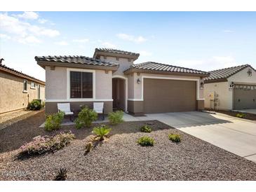 Inviting single-story home showcasing desert landscaping, a two-car garage, and a cozy seating area at 26947 W Adam Ave, Buckeye, AZ 85396