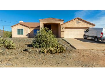 Tan single-story home with a desert landscape and a two-car garage at 49947 N 26Th Ave, New River, AZ 85087