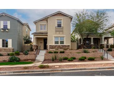 Charming two-story home with beige stucco, landscaped front yard, and decorative stone accents at 21031 W Elm Way Ct, Buckeye, AZ 85396