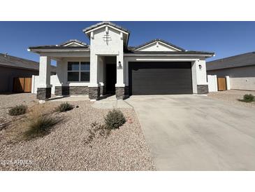 Charming single-story home with a dark-gray garage door, rock accents, and xeriscaped front yard at 36020 W San Ildefanso Ave, Maricopa, AZ 85138