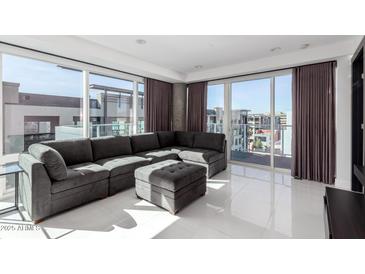 Bright living room featuring a sectional sofa, ottoman, floor-to-ceiling windows, and elegant tile floors at 4422 N 75Th St # 6007, Scottsdale, AZ 85251