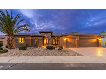 Inviting home exterior featuring a well-manicured yard, rock landscaping, and a three-car garage at 15558 W Big Sky Dr, Surprise, AZ 85374