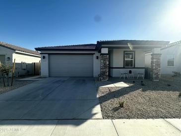 Charming single-story home featuring a two-car garage, desert landscaping, and covered porch with stone accents at 18231 W Paraiso Dr, Surprise, AZ 85387