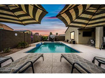 Inviting backyard pool with lounge chairs and umbrellas, perfect for outdoor relaxation and entertaining with a basketball hoop at 37340 W Merced St, Maricopa, AZ 85138