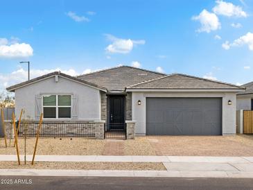 Charming single-story home with a gray exterior, a gray tiled roof, and a brick driveway at 4029 S 176Th Dr, Goodyear, AZ 85338