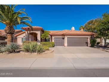 Charming single-story home featuring a three-car garage, a well-manicured lawn, and a desert landscape at 4628 E Gelding Dr, Phoenix, AZ 85032