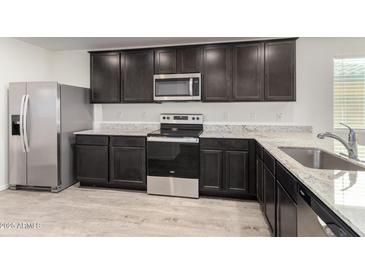 Modern kitchen features stainless steel appliances, gray cabinets and granite countertops at 8552 S 258Th Dr, Buckeye, AZ 85326
