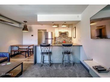 Bright kitchen featuring a breakfast bar with seating, stainless appliances, and an open dining area at 461 W Holmes Ave # 308, Mesa, AZ 85210