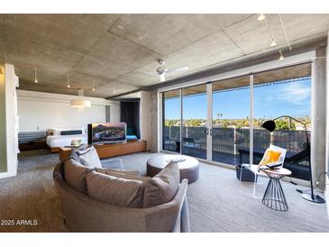 Bright living area featuring concrete ceilings, a modern sofa and sliding glass doors to a patio with city views at 6850 E Main St # 4404, Scottsdale, AZ 85251
