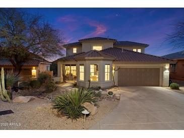 Stunning two-story home featuring desert landscaping, a tile roof, and a two-car garage, all beautifully illuminated at twilight at 11617 E Raintree Dr, Scottsdale, AZ 85255