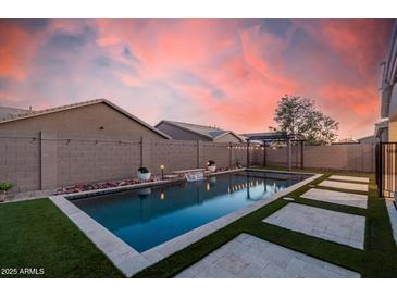 Inviting backyard pool with water feature, travertine deck, and lush artificial turf at 21255 W Ashland Ave, Buckeye, AZ 85396