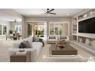 Staged living room featuring a ceiling fan, built-in shelving, and sliding glass doors to the backyard at 26635 W Covey Ln, Buckeye, AZ 85396