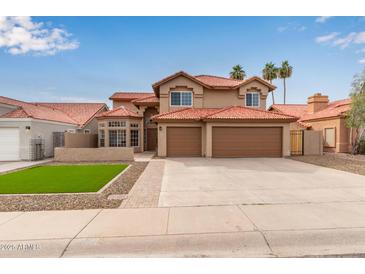 Two-story home featuring a red tile roof, desert landscaping, and an attached three-car garage at 4129 E Nighthawk Way, Phoenix, AZ 85048