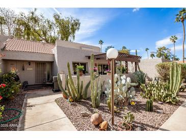 Charming front yard showcasing desert landscaping with cacti, succulents, and a cozy covered patio area at 7920 E Via Camello -- # 48, Scottsdale, AZ 85258